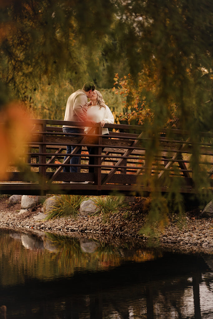 Engagement photo couple kissing on bridge