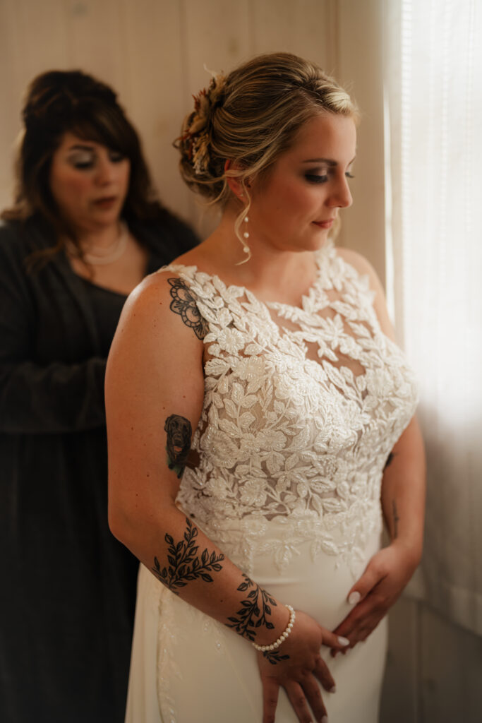 Bride portrait with mother helping her put her dress on